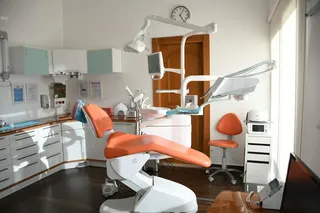 A bright dental room with an orange chair